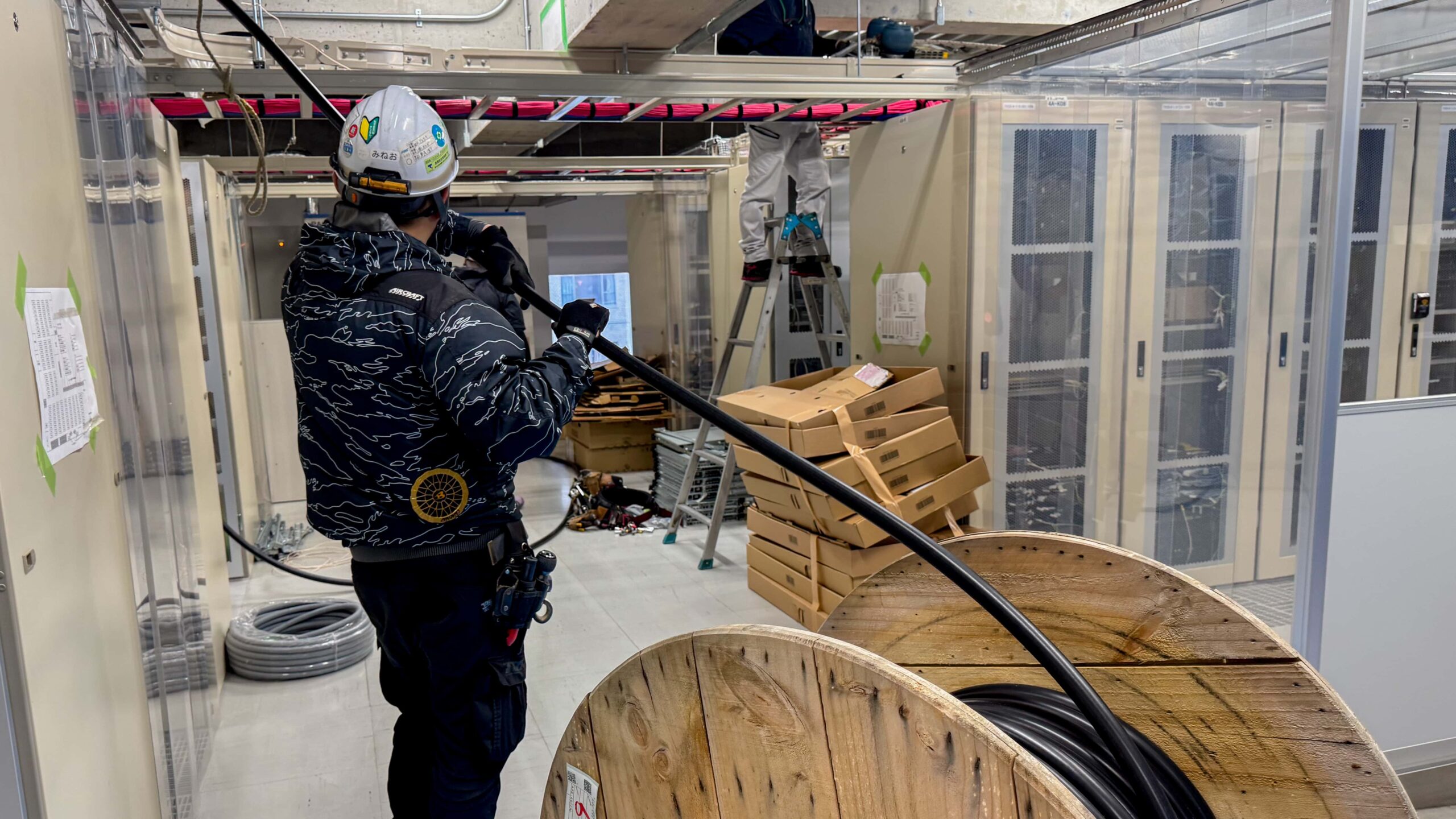 電気工事で、太くて黒いケーブルを持って作業する作業員の様子